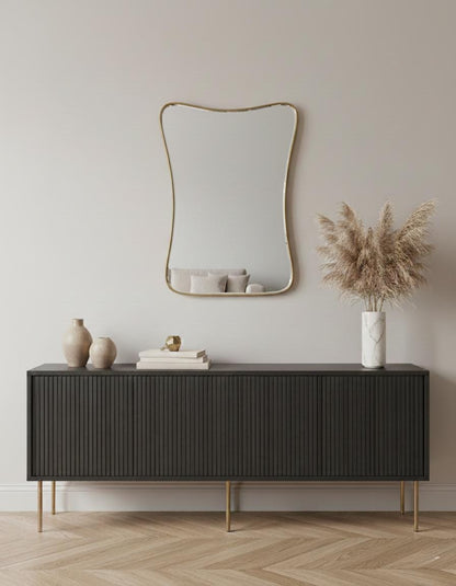 Handmade curved brass mirror above black console