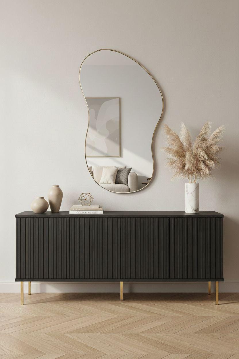 Sculptural organic brass wall mirror above black sideboard