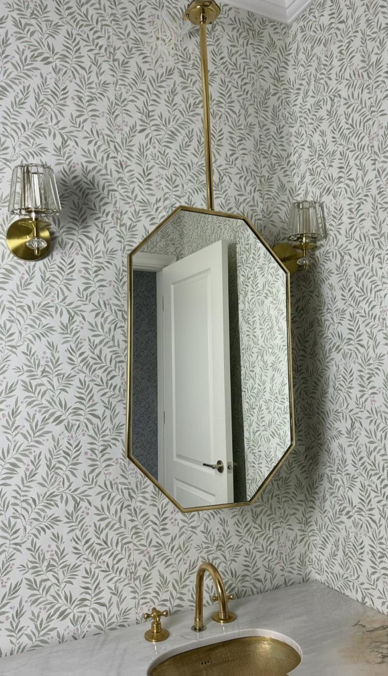 Octagonal mirror with brass wall sconces in powder room