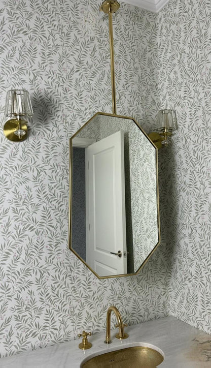Octagonal mirror with brass wall sconces in powder room