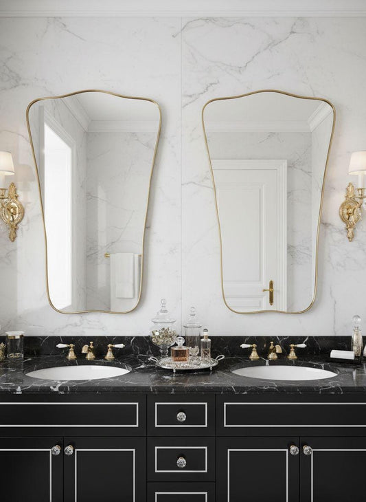 Asymmetrical shield-shaped brass mirror above double bathroom vanity